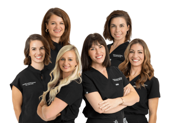 The Colonial Aesthetics & Wellness team — six clinicians and providers in black scrubs, smiling together.