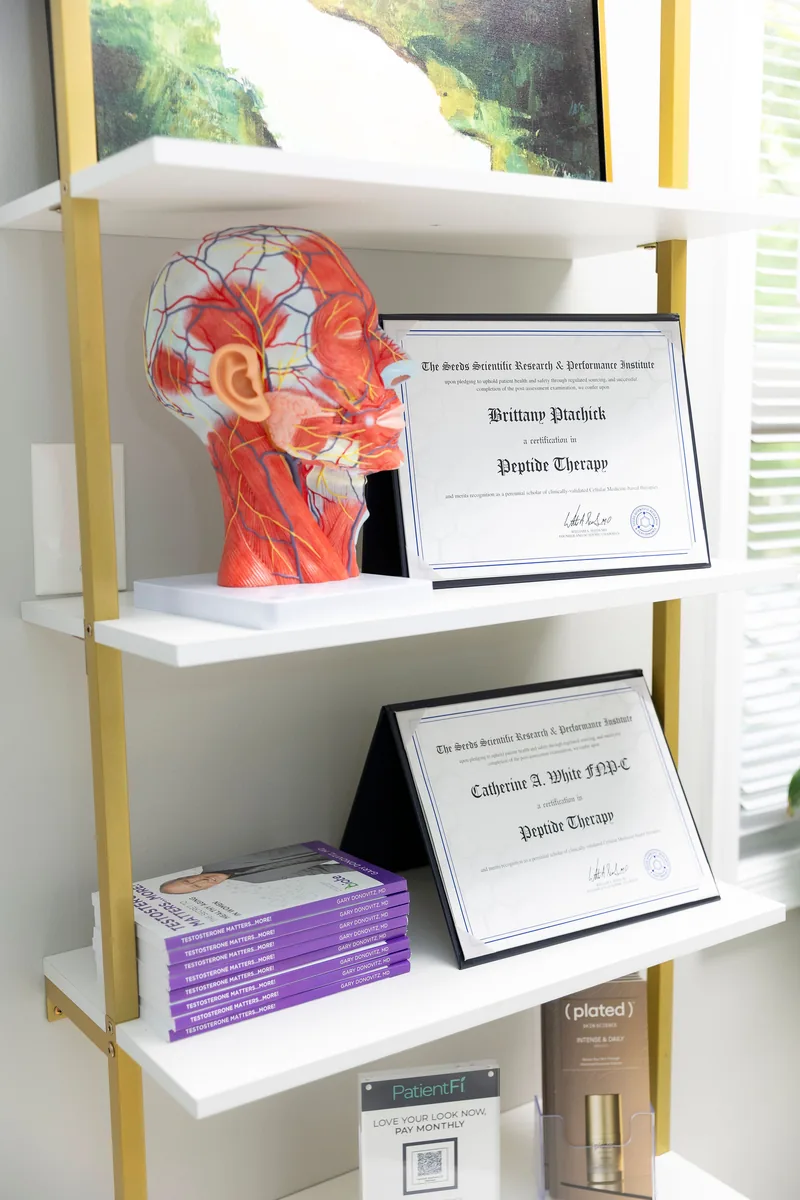 Peptide therapy certificates for Brittany Ptachick and Catherine A. White, FNP-C, displayed on a shelf