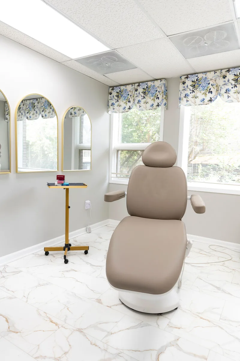 The injectable room at Colonial Aesthetics — a treatment chair, arched gold mirrors and a marble floor