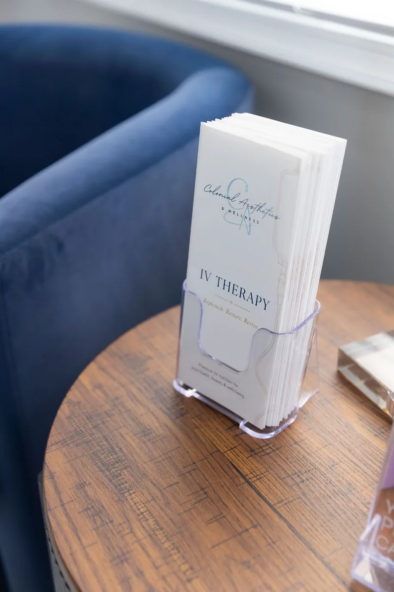 A Colonial Aesthetics IV Therapy brochure in a holder on a wooden side table